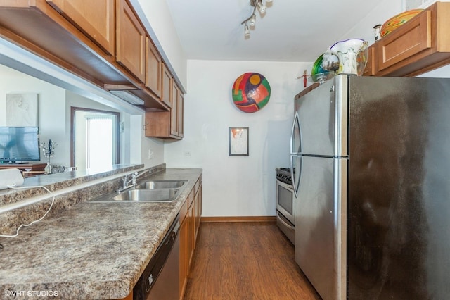 kitchen featuring stainless steel appliances, brown cabinets, dark wood-type flooring, and a sink