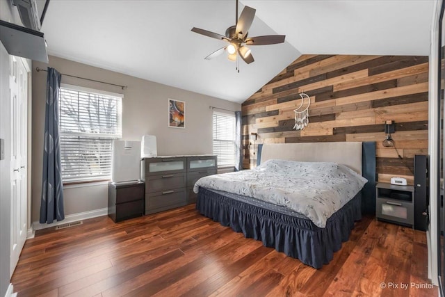 bedroom with dark hardwood / wood-style flooring, vaulted ceiling, ceiling fan, and wood walls