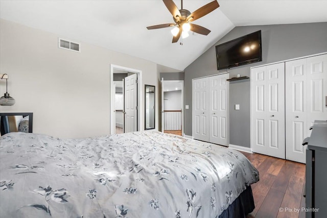 bedroom with ceiling fan, dark hardwood / wood-style floors, vaulted ceiling, and two closets