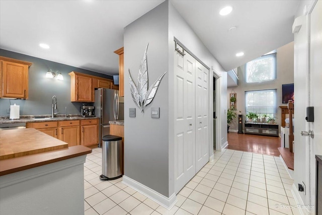 kitchen with lofted ceiling, sink, light tile patterned floors, and stainless steel appliances