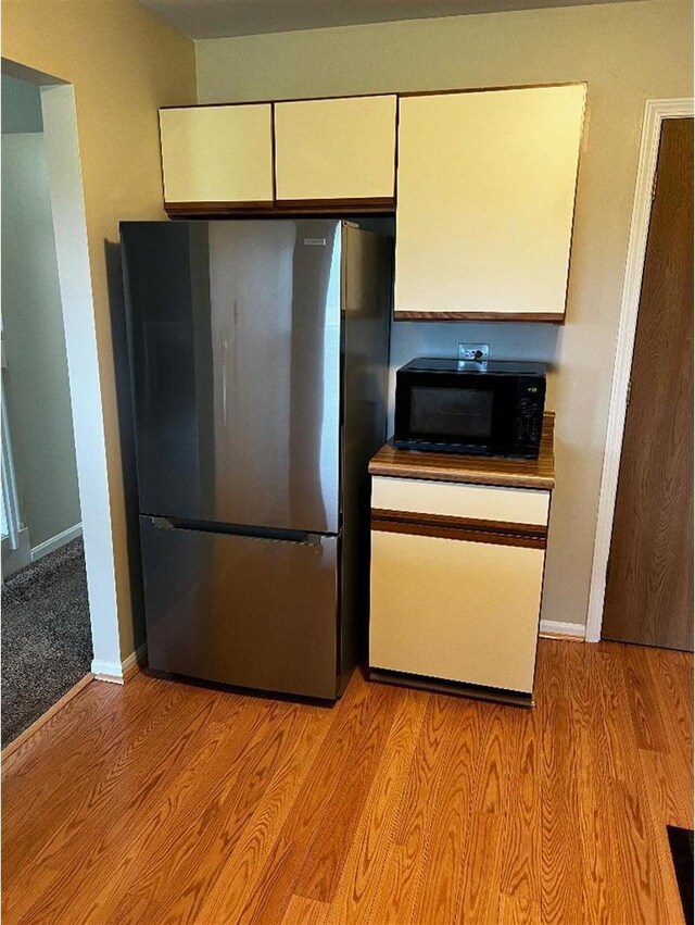 kitchen with white cabinets, stainless steel refrigerator, and light hardwood / wood-style floors