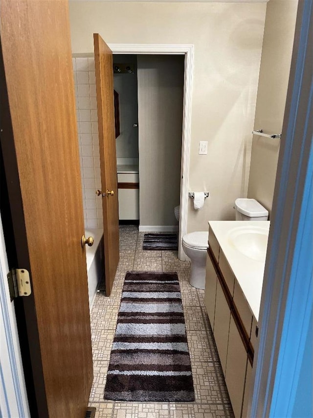 bathroom with vanity, a tub to relax in, and toilet