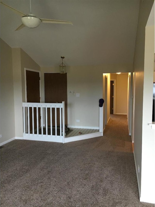 carpeted spare room featuring lofted ceiling and baseboards