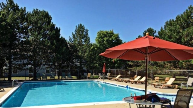 community pool with a patio and fence