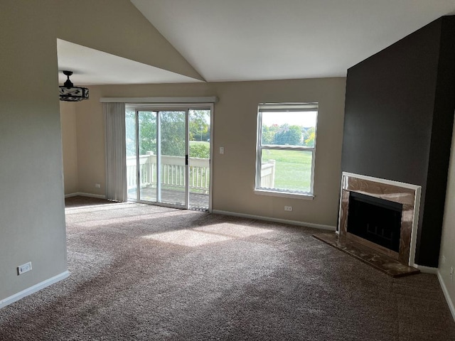 unfurnished living room featuring a premium fireplace, vaulted ceiling, carpet floors, and a healthy amount of sunlight