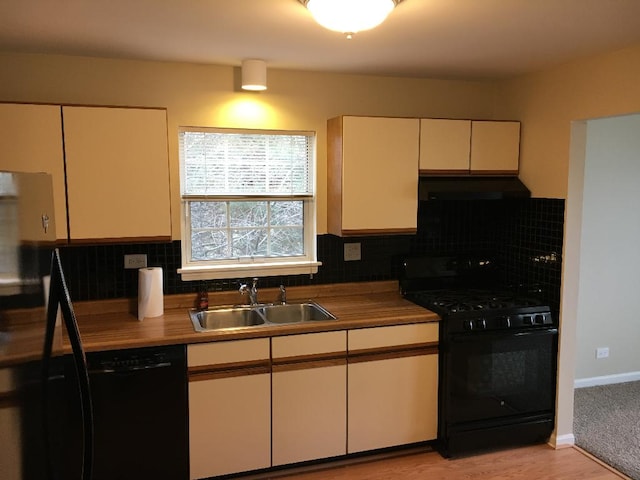 kitchen with black appliances, tasteful backsplash, under cabinet range hood, and a sink