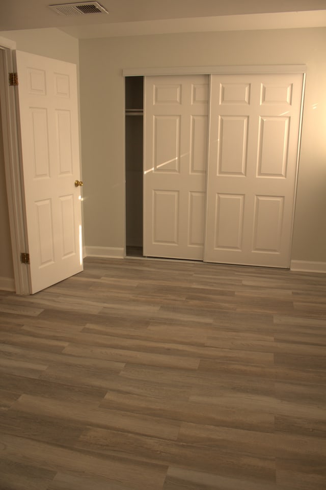 unfurnished bedroom with dark hardwood / wood-style flooring and a closet