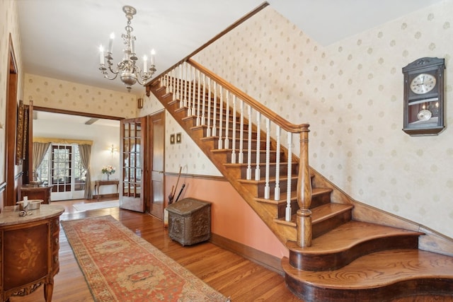 staircase with hardwood / wood-style flooring and an inviting chandelier