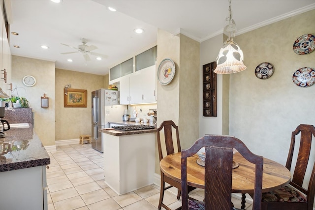 kitchen with light tile patterned floors, stainless steel refrigerator, ornamental molding, pendant lighting, and ceiling fan