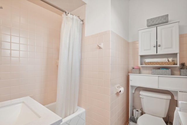 bathroom with toilet, shower / bathtub combination with curtain, and tile walls