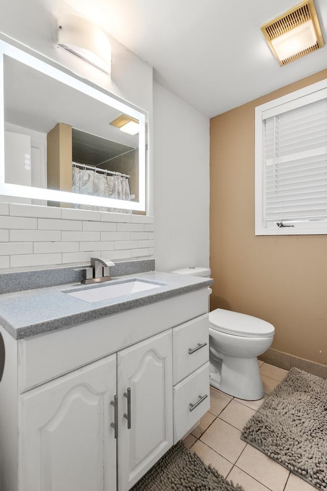 bathroom with tasteful backsplash, vanity, tile patterned floors, and toilet