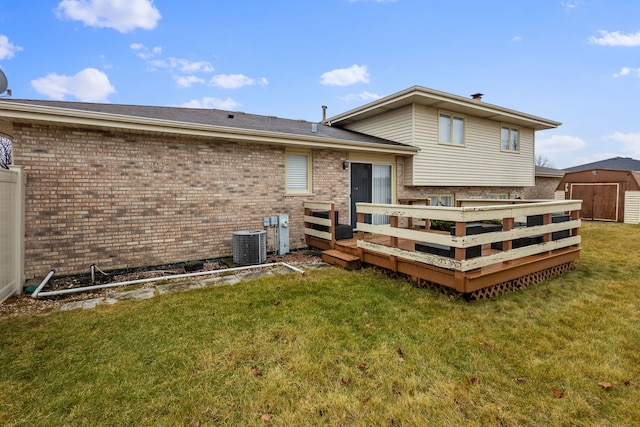 back of property featuring a wooden deck, central AC unit, a lawn, and a storage unit