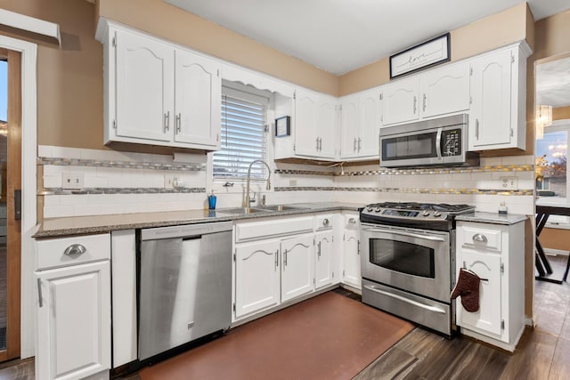 kitchen with sink, white cabinetry, appliances with stainless steel finishes, light stone countertops, and backsplash