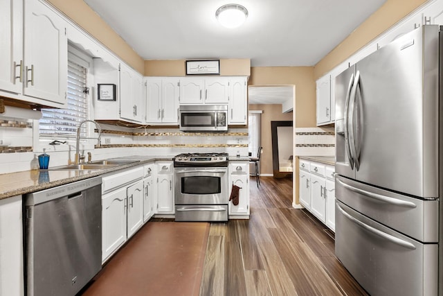 kitchen with dark wood-type flooring, sink, light stone counters, appliances with stainless steel finishes, and white cabinets