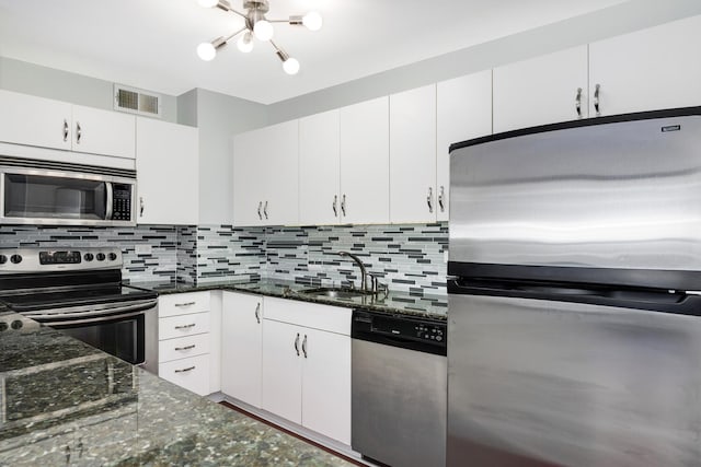 kitchen with white cabinetry, stainless steel appliances, sink, and dark stone counters