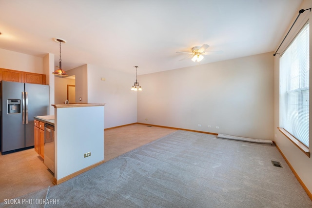 kitchen with ceiling fan, stainless steel appliances, light carpet, and hanging light fixtures