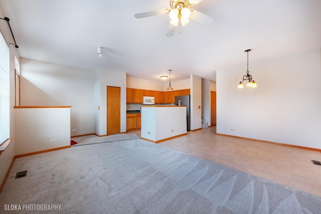 unfurnished living room featuring ceiling fan with notable chandelier and light colored carpet