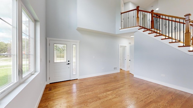 foyer entrance with light hardwood / wood-style floors and a high ceiling