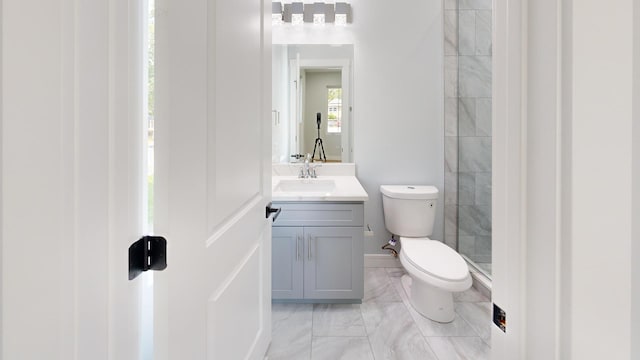 bathroom with vanity, toilet, and a tile shower