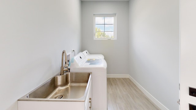 laundry area with separate washer and dryer, sink, and light hardwood / wood-style flooring