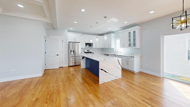 kitchen with hanging light fixtures, stainless steel appliances, and white cabinets