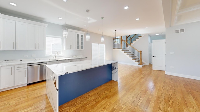 kitchen with sink, a center island, stainless steel dishwasher, pendant lighting, and white cabinets