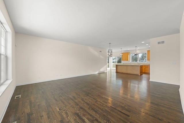 unfurnished living room featuring dark wood-type flooring and a chandelier