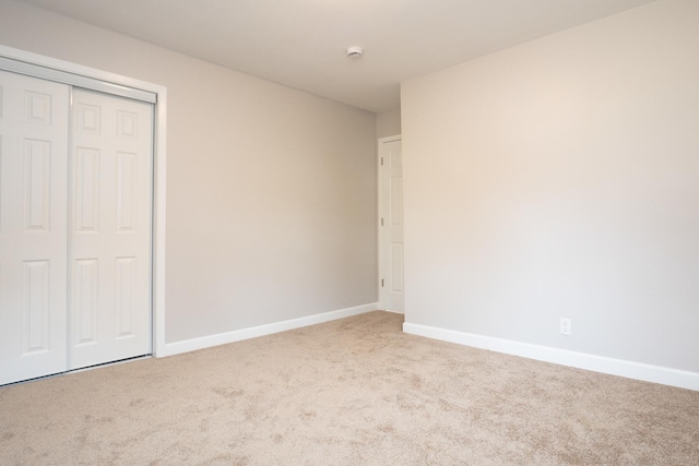 unfurnished bedroom featuring light carpet and a closet