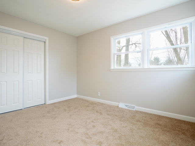 unfurnished bedroom with light colored carpet and a closet