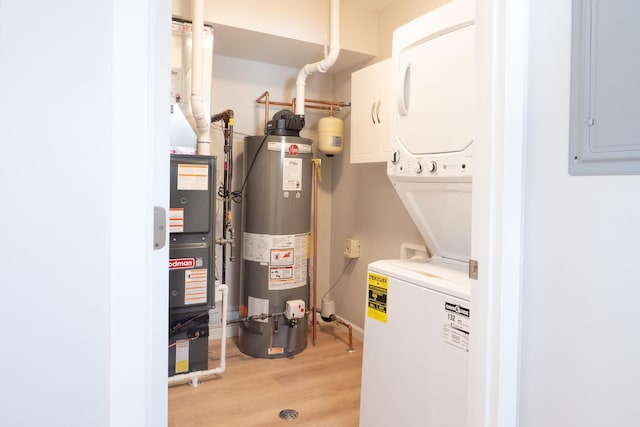 utilities with stacked washer and dryer, electric panel, and gas water heater