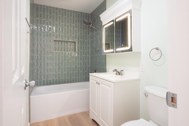 full bathroom with tiled shower / bath, wood-type flooring, toilet, and vanity