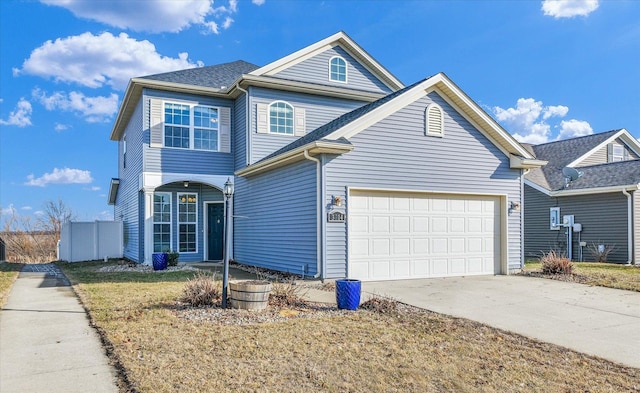 traditional-style house with a garage, driveway, and fence