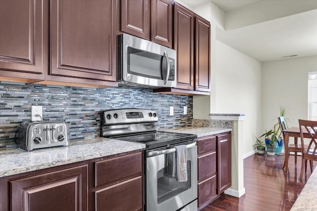 kitchen featuring tasteful backsplash, baseboards, light stone counters, dark wood-type flooring, and stainless steel appliances