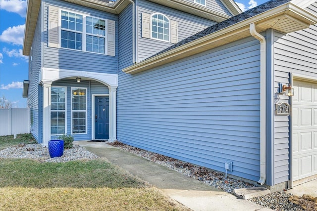 view of exterior entry with a garage and fence