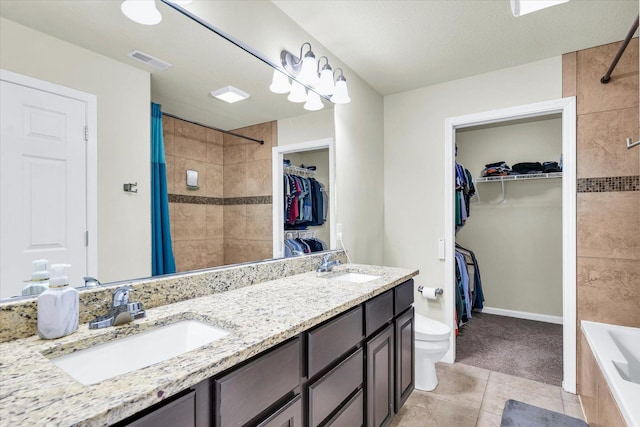 bathroom with a sink, double vanity, a walk in closet, and visible vents