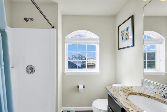 full bath featuring a shower, baseboards, vanity, and toilet