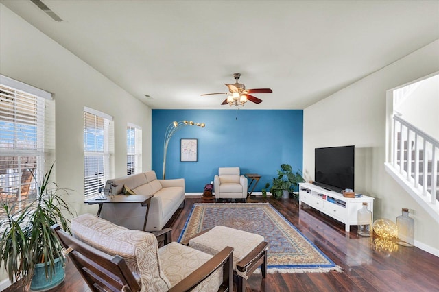 living room featuring a ceiling fan, dark wood-style flooring, baseboards, and stairs