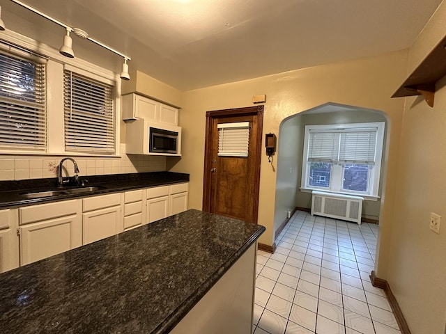 kitchen featuring sink, white cabinetry, light tile patterned floors, radiator, and backsplash