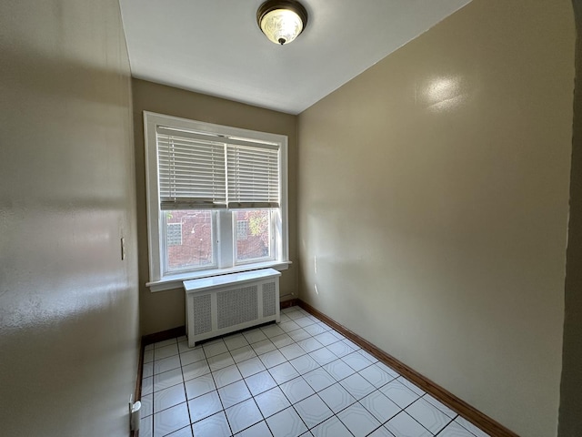 tiled spare room featuring radiator heating unit