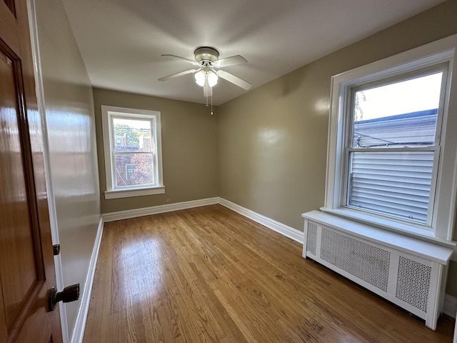 unfurnished room featuring radiator, hardwood / wood-style flooring, and ceiling fan