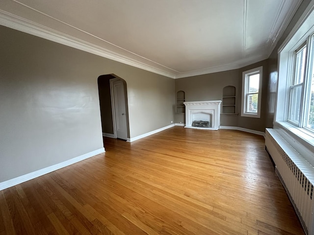 unfurnished living room featuring ornamental molding, radiator heating unit, light hardwood / wood-style floors, and built in features