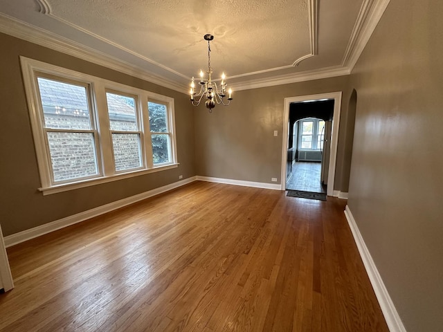 unfurnished dining area with hardwood / wood-style flooring, ornamental molding, and an inviting chandelier