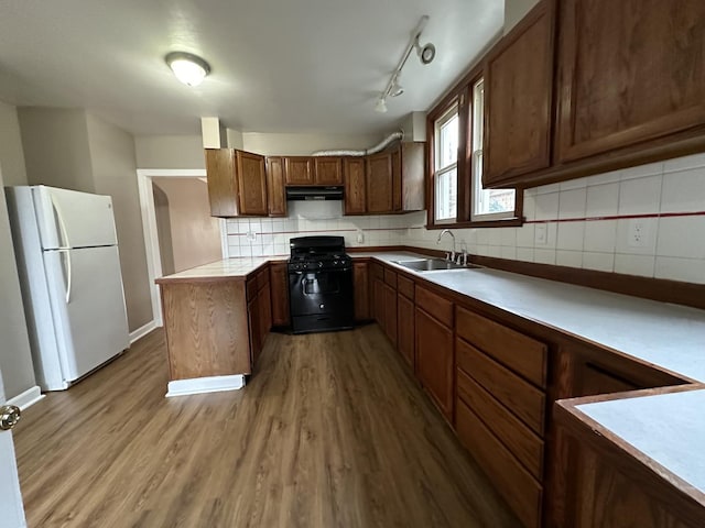 kitchen with sink, gas stove, light hardwood / wood-style flooring, white fridge, and decorative backsplash