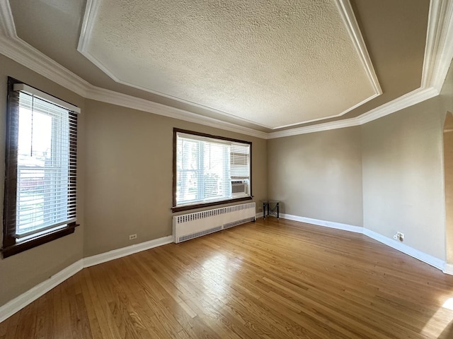 spare room with hardwood / wood-style flooring, radiator, a wealth of natural light, and a textured ceiling