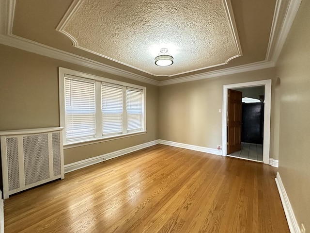 spare room featuring ornamental molding, radiator, light hardwood / wood-style flooring, and a textured ceiling