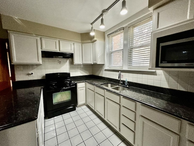 kitchen with white cabinetry, gas stove, sink, and dark stone countertops