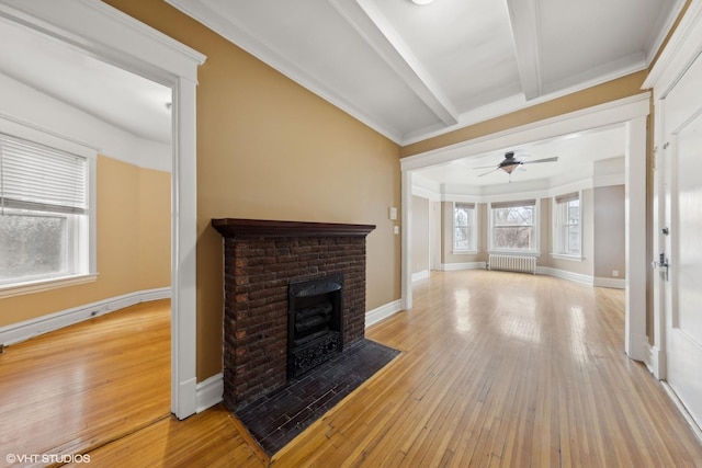 unfurnished living room featuring beamed ceiling, a brick fireplace, radiator, and light hardwood / wood-style flooring