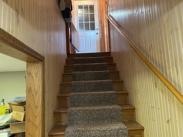 stairway featuring wood walls