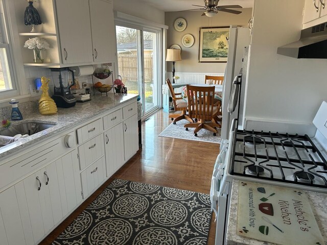 kitchen featuring sink, white cabinets, light stone countertops, dark wood-type flooring, and white appliances