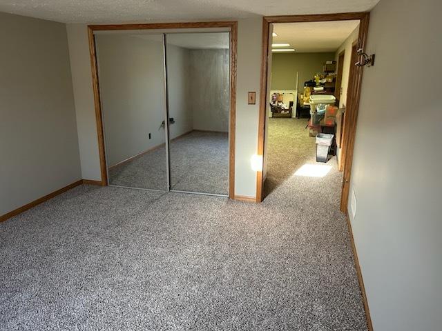 unfurnished bedroom with carpet floors, a closet, and a textured ceiling